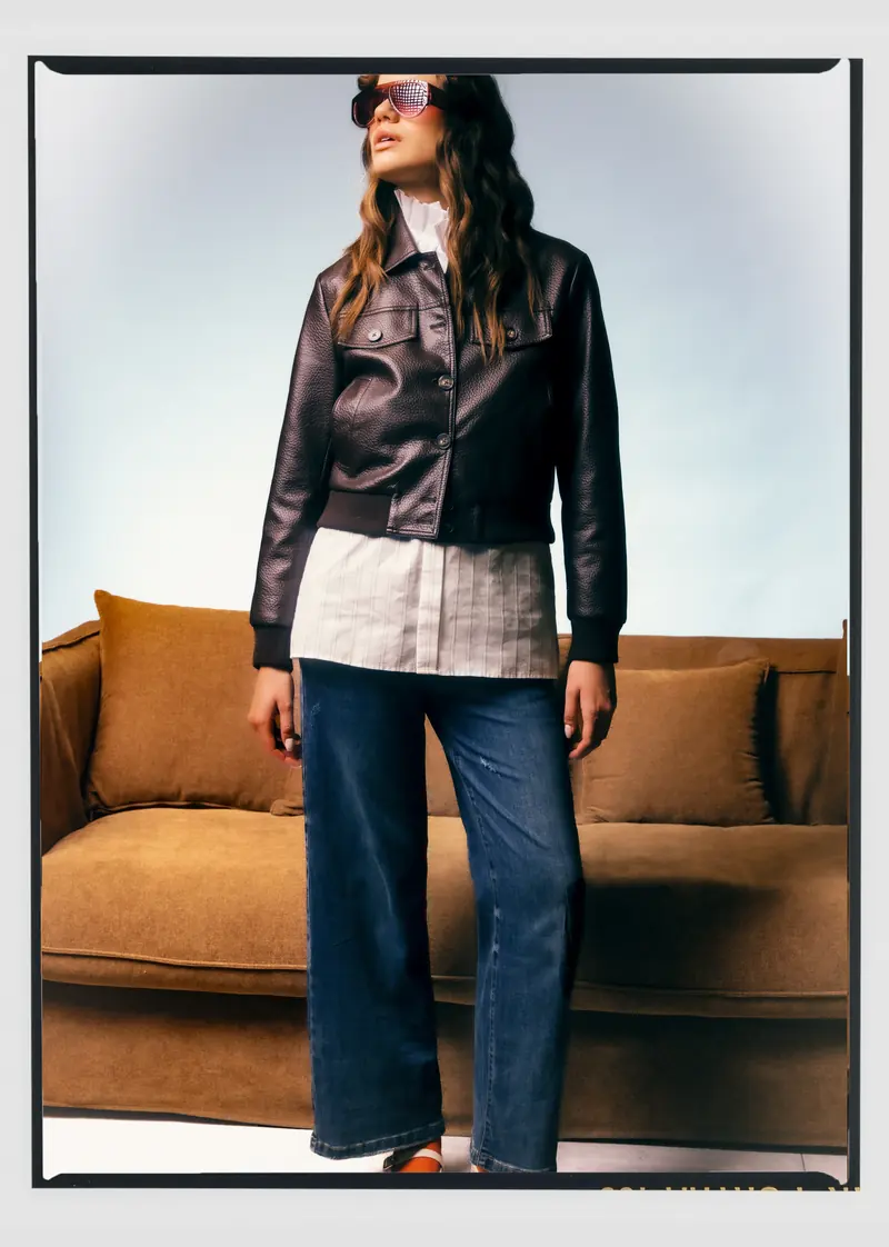Look L12, Fall Winter 26/27: giubbotto corto nero lucido, camicia bianca e jeans