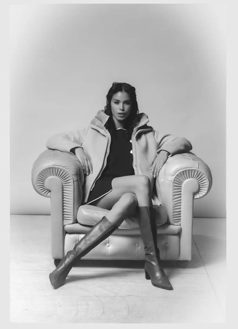 Look L27, Fall Winter 26/27: in bianco e nero, giaccone chiaro su una poltrona Chesterfield