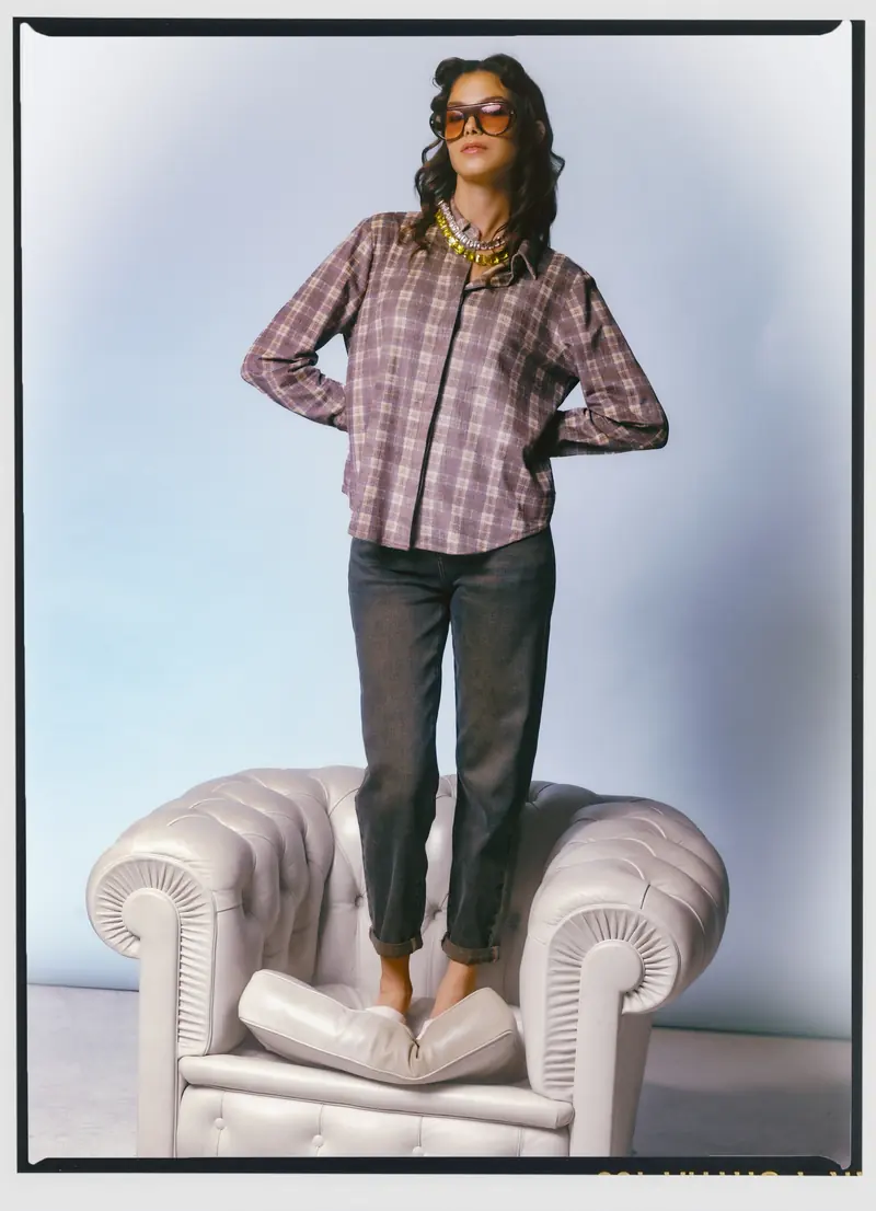 Look L49, Fall Winter 26/27: camicia a quadri, in piedi su una poltrona Chesterfield