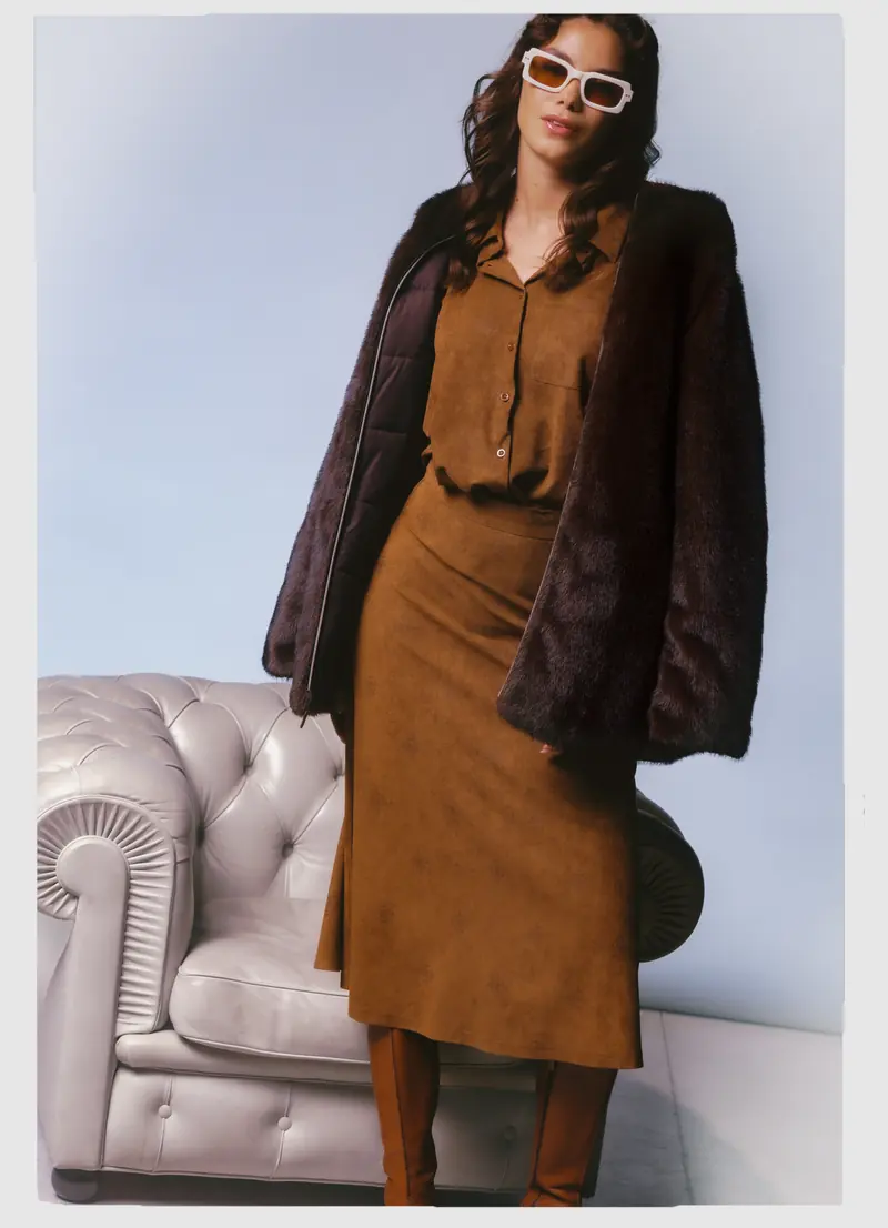Look L57, Fall Winter 26/27: giubbotto di pelliccia scuro accanto alla Chesterfield