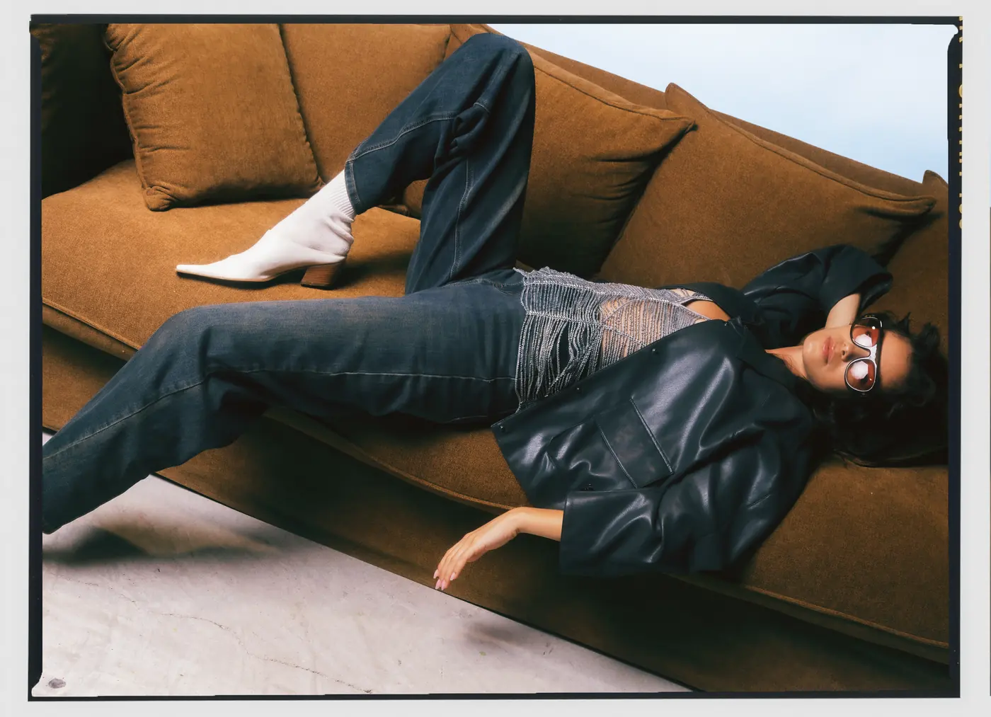 Sdraiata sul divano, giacca nera e jeans: la campagna Fall Winter 26/27
