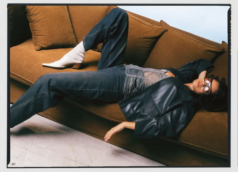 Look L8, Fall Winter 26/27: sdraiata sul divano, giacca nera e jeans